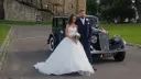 Bride and groom standing beside blue Austin 18 York vintage wedding car at Kent wedding venue.