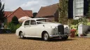 Classic Bentley S1 in Old English White parked at a countryside wedding venue in Kent, showing the elegant side profile and timeless British luxury styling.