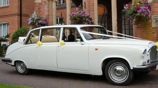 Classic white Daimler limousine landaulette wedding car with roof open and wedding ribbons in Kent.