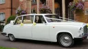 Classic white Daimler limousine landaulette wedding car with roof open and wedding ribbons in Kent.
