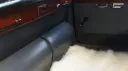 Rear passenger area inside classic Daimler limousine with occasional seat folded down for extra legroom.