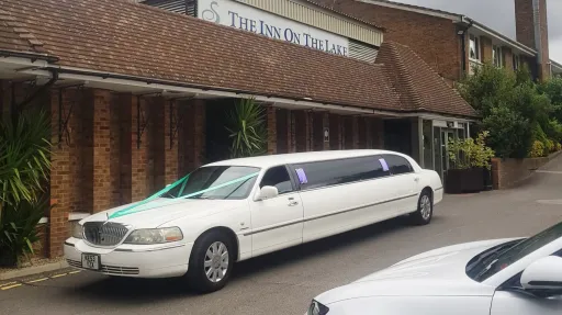 White Lincoln Town Car stretch limousine parked outside wedding venue with long limousine body styling.