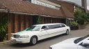 White Lincoln Town Car stretch limousine parked outside wedding venue with long limousine body styling.