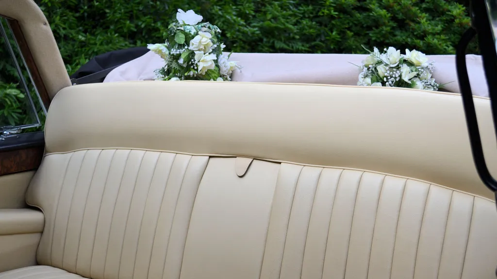 Rear cream leather bench seating inside classic Daimler limousine wedding car.