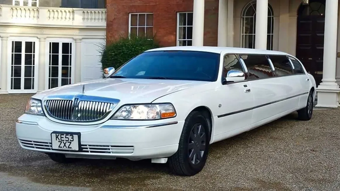 White American Lincoln Town Car stretch limousine with chrome grille parked outside venue in Kent.
