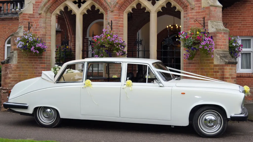 Classic white Daimler limousine landaulette parked outside church venue in Kent.