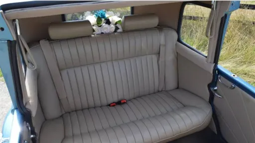 Cream leather rear interior of a blue vintage Beauford wedding car with spacious seating and classic chauffeur driven styling.