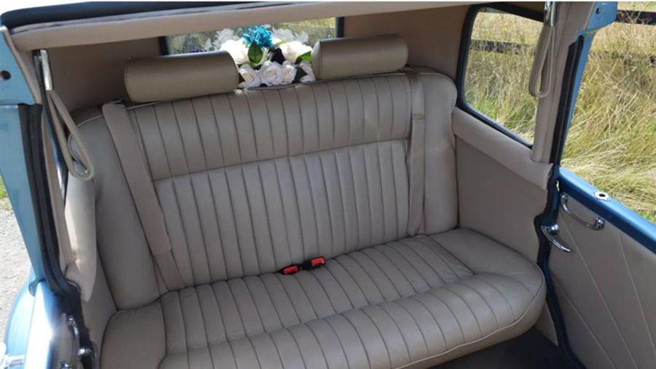 Cream leather rear interior of a blue vintage Beauford wedding car with spacious seating and classic chauffeur driven styling.