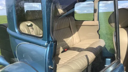 Cream leather interior inside a blue four door Beauford wedding car, showing spacious rear seating and vintage detailing.