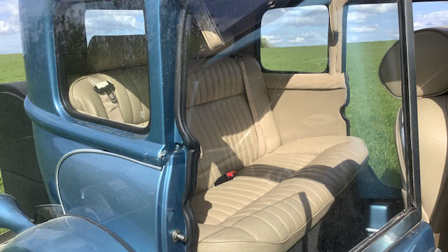 Cream leather interior inside a blue four door Beauford wedding car, showing spacious rear seating and vintage detailing.