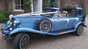 Blue four door Beauford wedding car decorated with white wedding ribbons and bows, photographed outside a wedding venue.