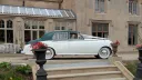 Classic 1957 Rolls Royce Silver Cloud I wedding car in white and dark green parked outside a Sussex wedding venue in West Sussex. Vintage chauffeur driven Rolls Royce with wedding ribbons and timeless luxury styling.