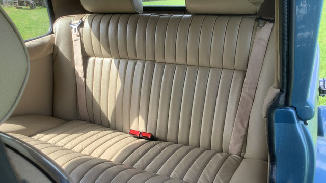 Cream leather rear seating inside a chauffeur driven blue Beauford wedding car with vintage luxury interior styling.