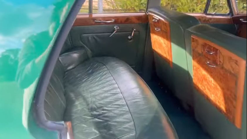 Interior seating inside a white 1957 Rolls Royce Silver Cloud I with matching dark green leather and polished wood trim. Luxury classic wedding transport available in Littlehampton, West Sussex.