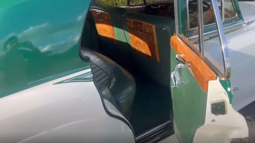Rear passenger interior of a 1957 Rolls Royce Silver Cloud I with dark green leather seats, polished walnut trim and vintage luxury detailing. Elegant classic Rolls Royce wedding car interior in Littlehampton, West Sussex.
