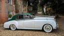 Right side view of a 1957 Rolls Royce Silver Cloud I in white with contrasting dark green roof and matching green leather interior in West Sussex. Luxury classic wedding car photographed outdoors near Littlehampton.
