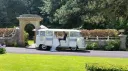 Classic cream and light blue Volkswagen VW Split Screen Campervan parked outside a wedding venue in Southport, Lancashire, with the bride and groom standing beside the retro wedding campervan surrounded by gardens and stone archways.