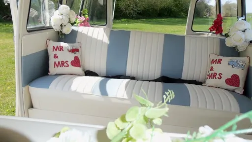 Interior of a classic Volkswagen VW Split Screen Campervan featuring forward facing striped cream and blue leather bench seating with personalised Mr & Mrs wedding cushions and floral décor.