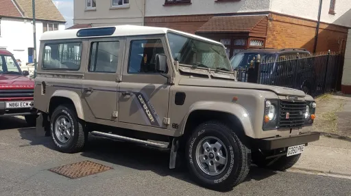Beige Land Rover Defender wedding car with cream roof parked outside residential property in Kent.