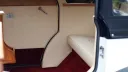 Close up view if rear cabin interior with cream leather and red burgundy carpet.