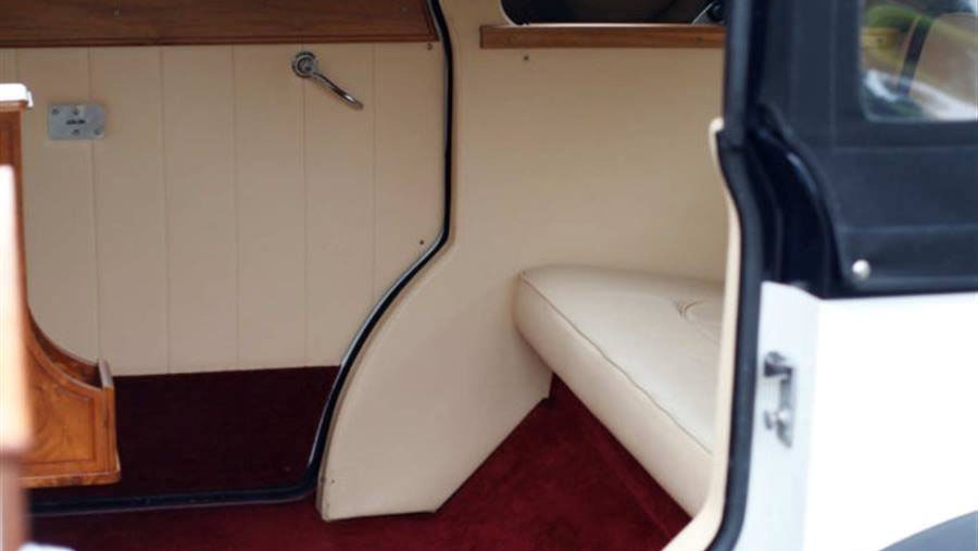 Close up view if rear cabin interior with cream leather and red burgundy carpet.