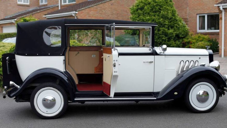 Right side view of Black and Ivory Regent car with rear passenger door open showing cream leather seats and burgundy carpet