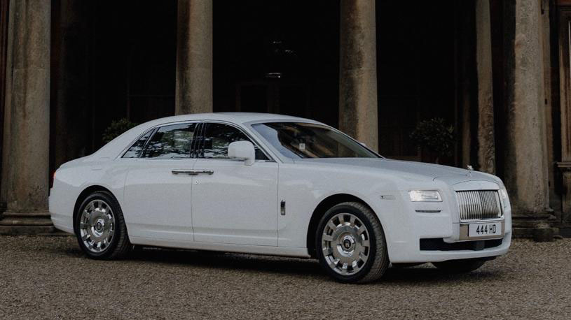 White Rolls-Royce Ghost parked in front of an elegant building.