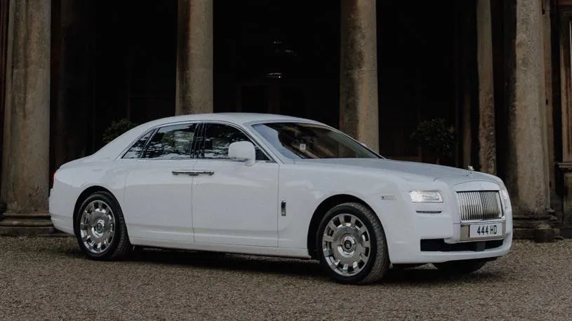 White Rolls-Royce Ghost parked in front of an elegant building.