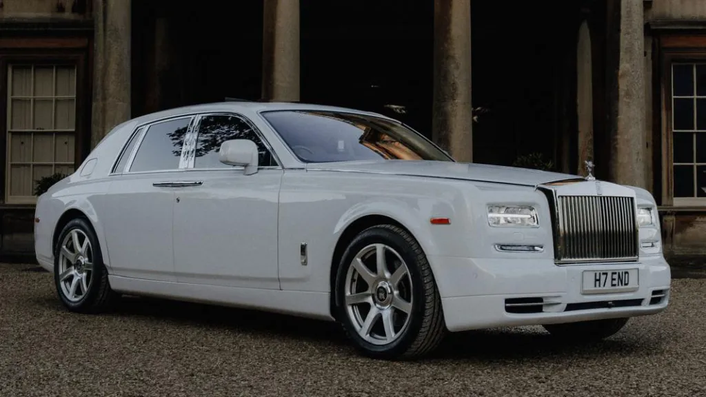 Side view of a white Rolls-Royce Phantom parked in fron of a venue