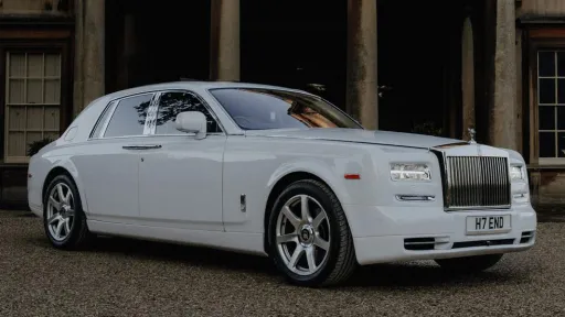 Side view of a white Rolls-Royce Phantom parked in fron of a venue