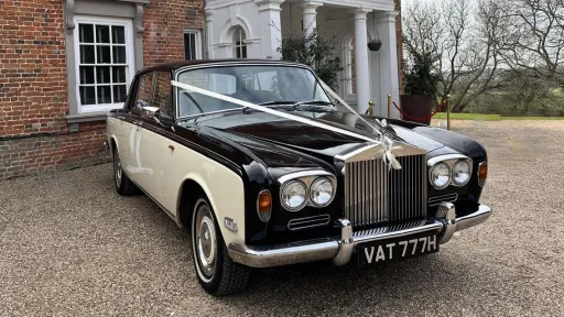 Black and ivory 1970 Rolls-Royce Silver Shadow Mark 1 wedding car parked on a gravel driveway.