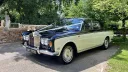 Front left side view of a black and ivory Rolls-Royce Silver Shadow Mark 1 parked in the countryside.