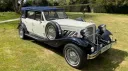 Blue and ivory Beauford wedding car with soft top roof parked at countryside venue.