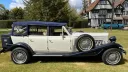 Right side view of ivory and navy Beauford convertible wedding car parked on grass in Kent.