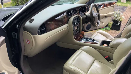 Luxury cream leather seats and polished wood dashboard inside Jaguar stretch limousine.