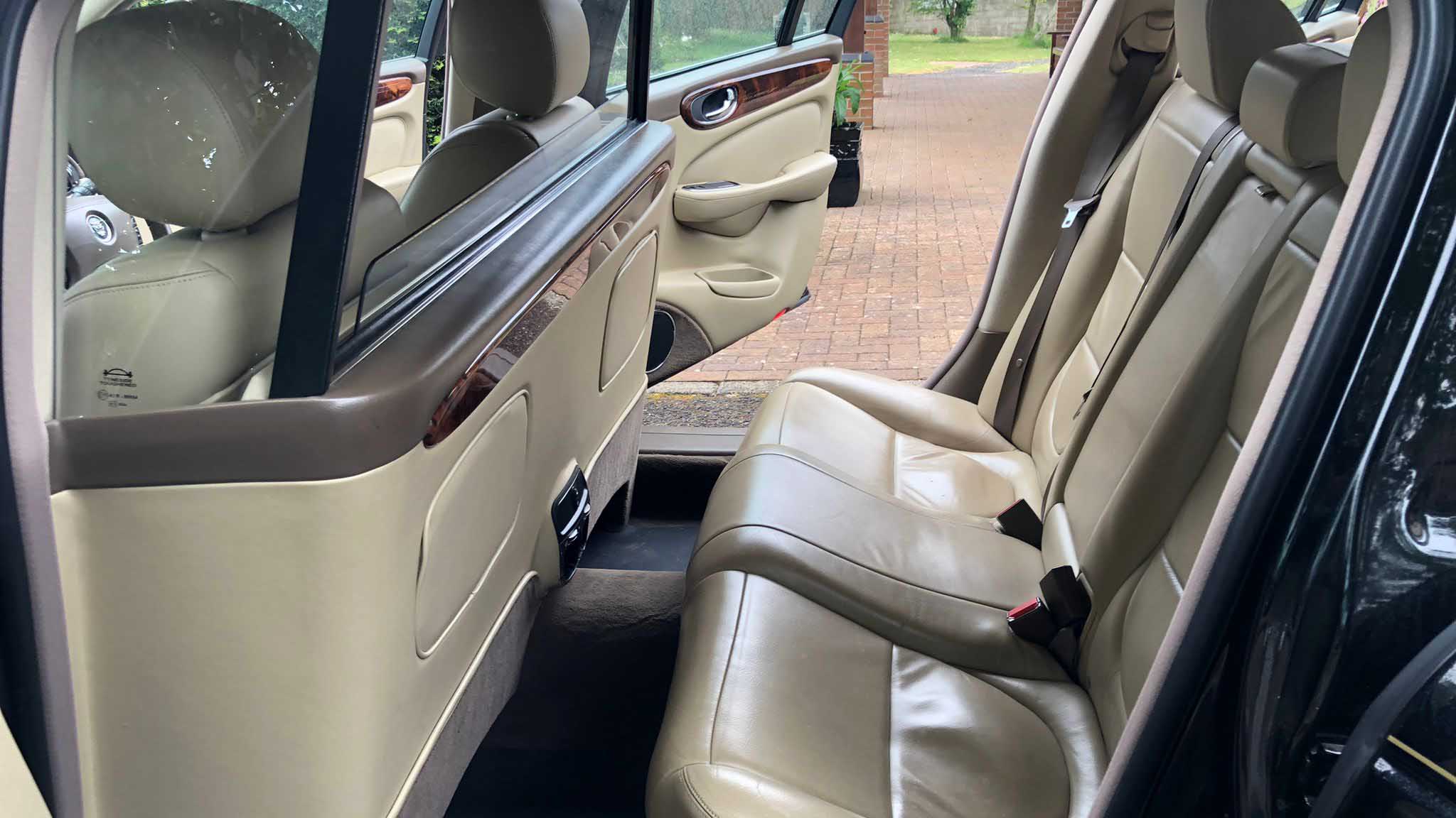 Middle row cream leather seating inside black Jaguar stretched limousine wedding car.