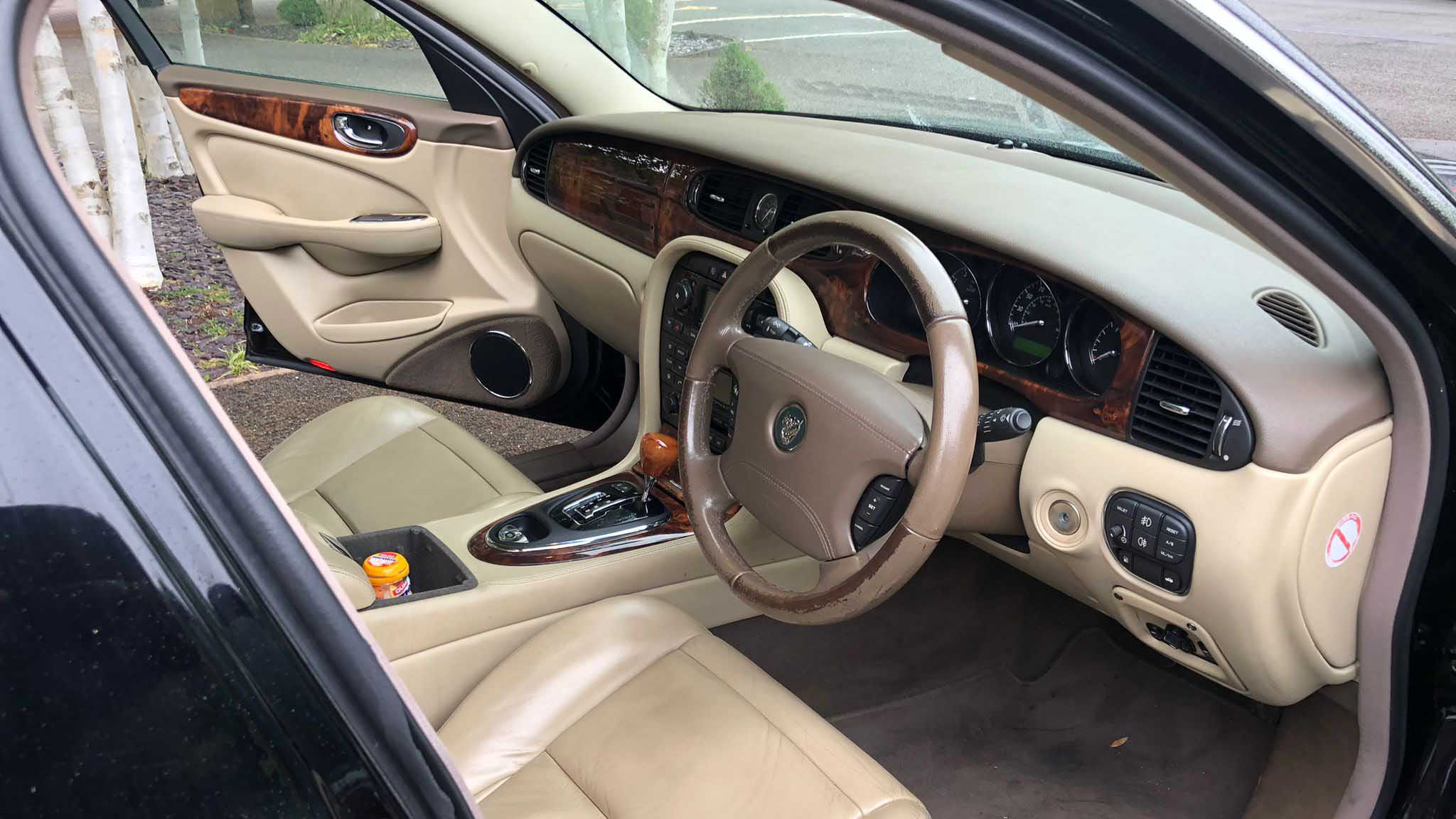 Driver’s seat and dashboard inside black Jaguar stretch limousine with cream leather interior.