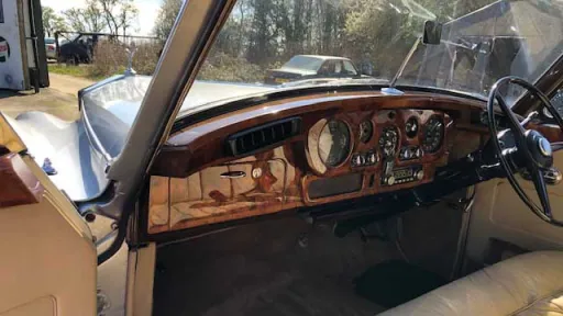 Driver’s view inside Rolls-Royce Silver Cloud showing wooden dashboard and classic steering wheel.
