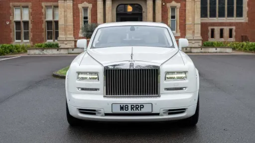 Front view of white Rolls-Royce Phantom Series II EWB with signature chrome grille and Spirit of Ecstasy.