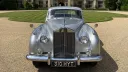 Front view of silver Rolls-Royce Silver Cloud with chrome grille and Spirit of Ecstasy emblem.