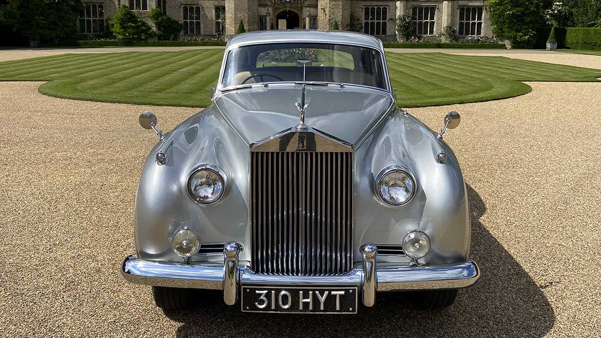 Front view of silver Rolls-Royce Silver Cloud with chrome grille and Spirit of Ecstasy emblem.