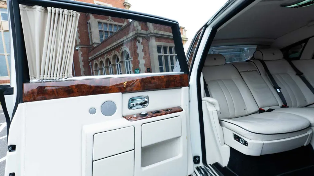 White leather rear seating inside Rolls-Royce Phantom Series II EWB with polished wood trim.