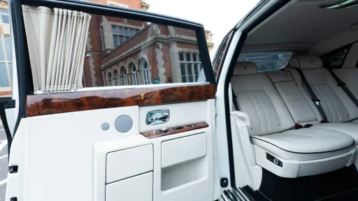 White leather rear seating inside Rolls-Royce Phantom Series II EWB with polished wood trim.