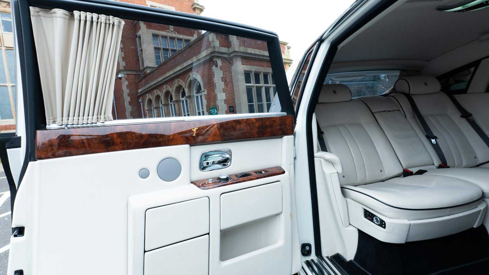 White leather rear seating inside Rolls-Royce Phantom Series II EWB with polished wood trim.