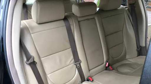 Rear cream leather bench seating inside luxury black Jaguar stretch limousine.