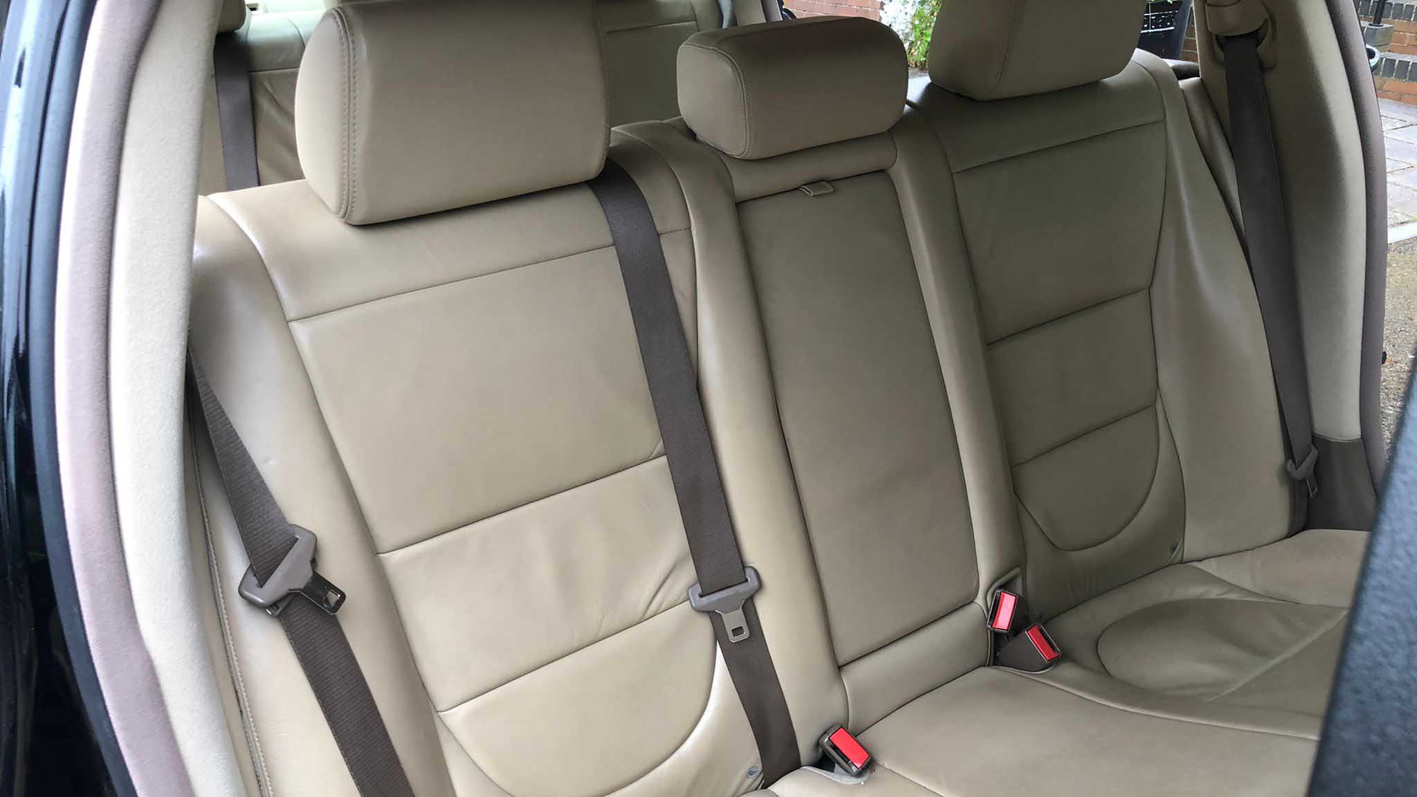 Rear cream leather bench seating inside luxury black Jaguar stretch limousine.