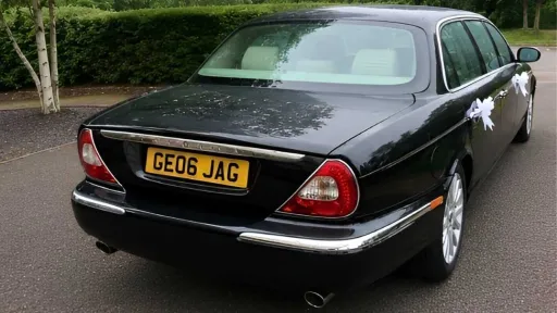 Rear view of black Jaguar stretch limousine wedding car parked on driveway.