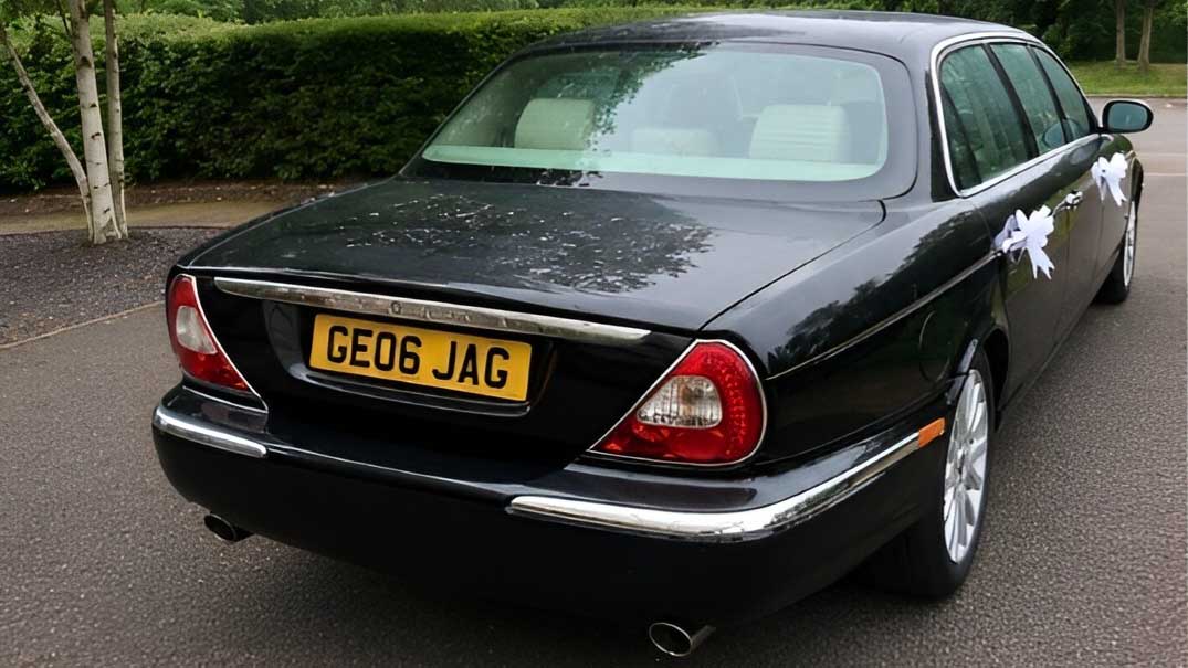 Rear view of black Jaguar stretch limousine wedding car parked on driveway.