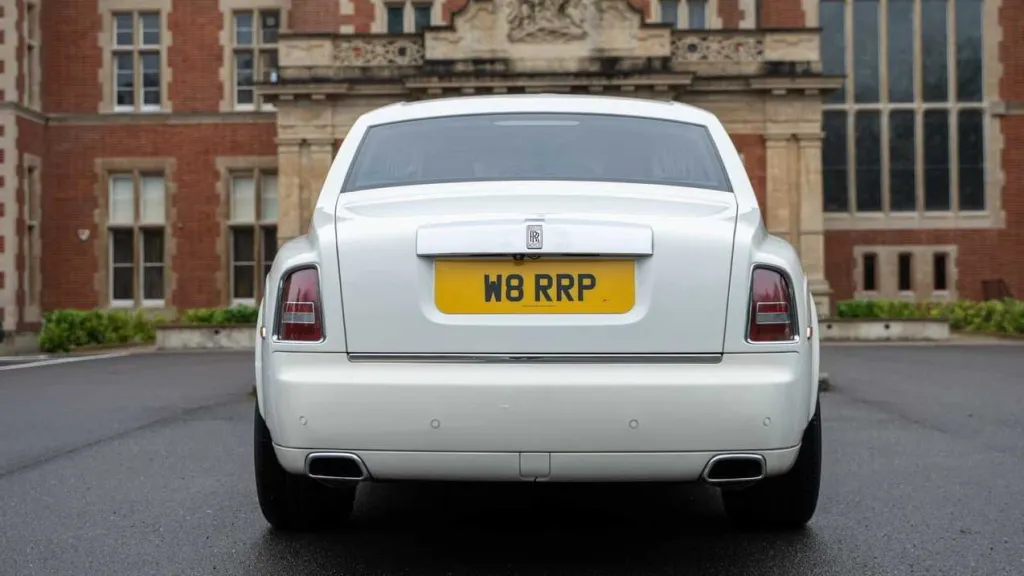 Rear view of white Rolls-Royce Phantom Series II EWB parked outside luxury venue.