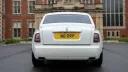 Rear view of white Rolls-Royce Phantom Series II EWB parked outside luxury venue.